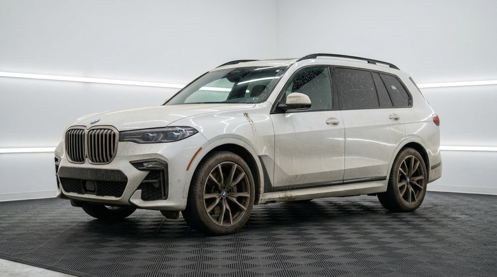 White BMW X7 at intake — road film, water spots, and dull paint